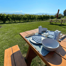 Load image into Gallery viewer, Eco friendly and sustainable linens, dining ware and Flow water bottles are set elegantly on a picnic table next to the organic vineyards of Sperling Vineyards in the Okanagan Valley in Kelowna, BC.  | Farm to Glass Wine Tours