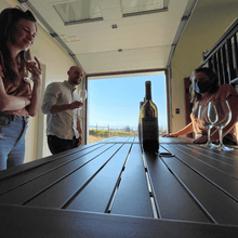 Load image into Gallery viewer, A couple enjoys the wine tasting in a quaint garage that has been coverted into a tasting room at Nagging Doubt Winery in Kelowna, BC.