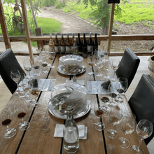 Load image into Gallery viewer, The Grand Epicurean Private Reserve Tasting set up at Covert Farms Family Estate in Oliver, BC. A luxurious experience awaits as guests sample exclusive wines amidst the beautiful estate surroundings | Farm to Glass Wine Tours