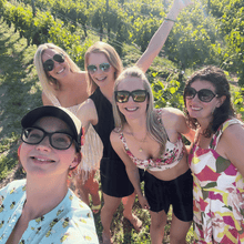 Load image into Gallery viewer, Four happiest guests along with owner and guide Jess Hopwood of Farm to Glass Wine Tours pose and smile in delight for a selfie after a day of wine tasting on their private Okangan wine tour with rows of vineyards in the background.  | Farm to Glass Wine Tours
