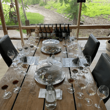 Load image into Gallery viewer, The Grand Epicurean Private Reserve Tasting set up at Covert Farms Family Estate in Oliver, BC. A luxurious experience awaits as guests sample exclusive wines amidst the beautiful estate surroundings | Farm to Glass Wine Tours
